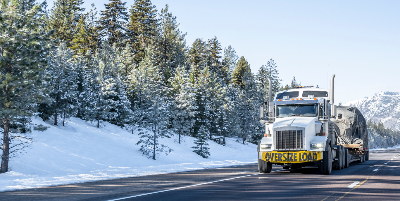 oversized truck driving down snowy highway featured image