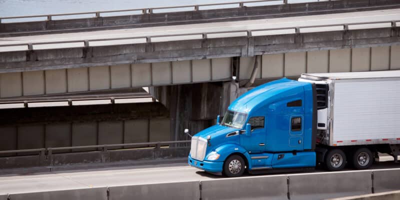 blue freight truck driving on highway