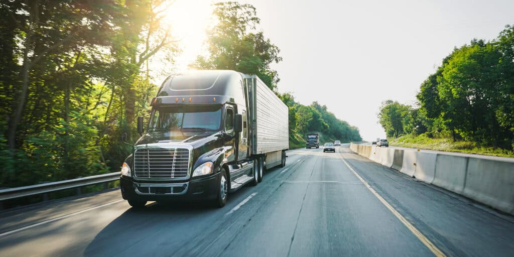 freight truck on a highway with sun shining in the background