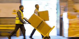 two people moving shipping boxes in a warehouse
