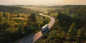 semi truck driving away on a sunset lit highway