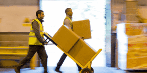 two people moving shipping boxes in a warehouse
